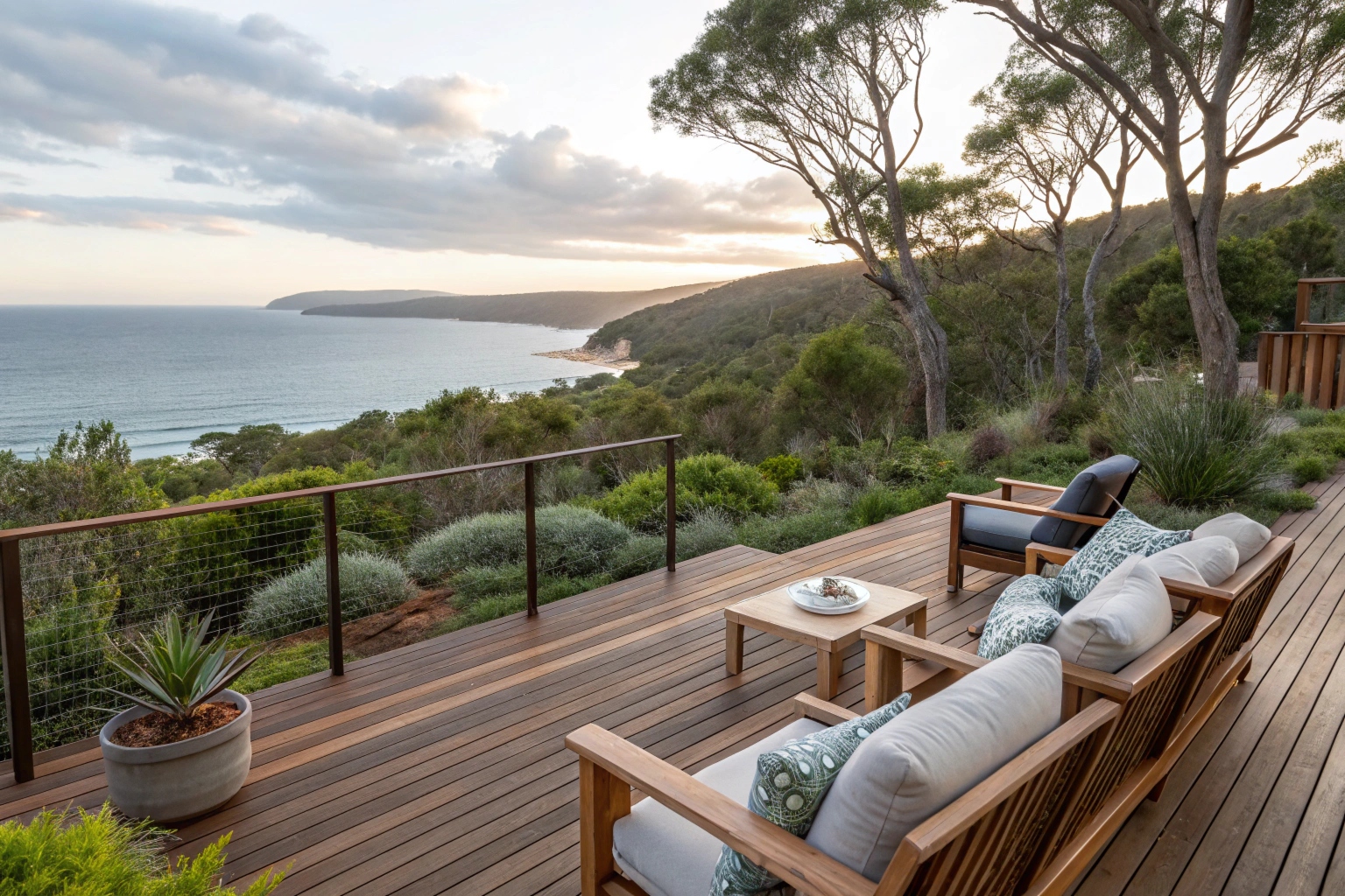 potted gum timber deck overlooking a coastal backyard with native Australian plants, outdoor furniture with cushions