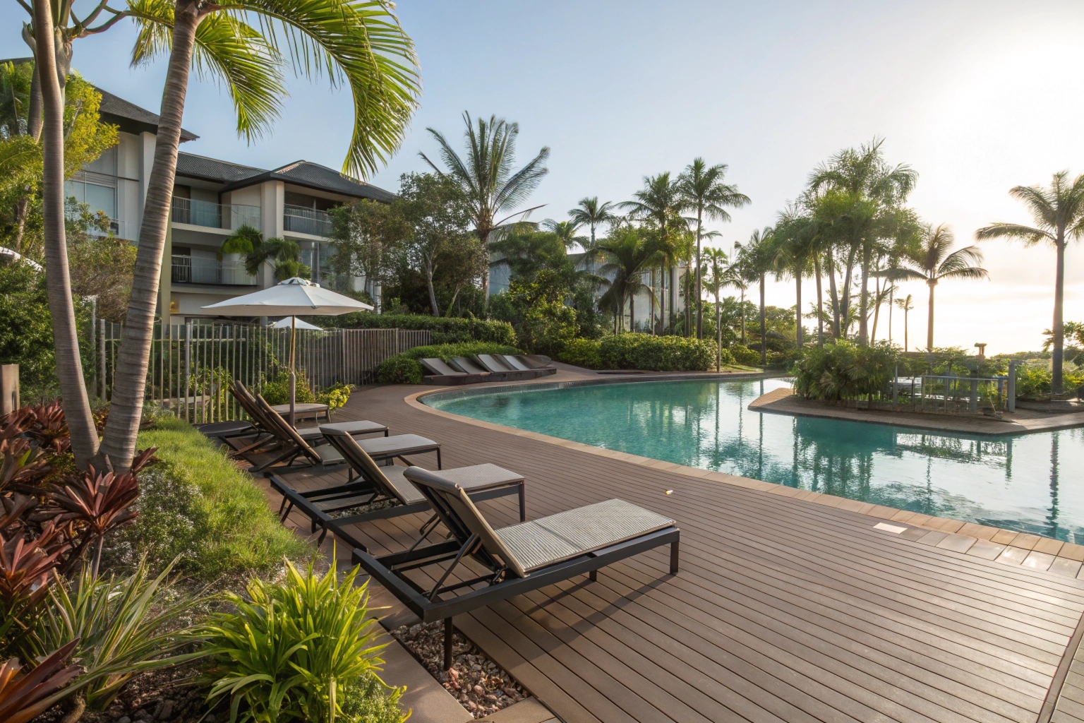 omposite pool deck surrounding resort-style pool, lounge chairs on composite surface, tropical Queensland landscaping, sunny day with palm trees